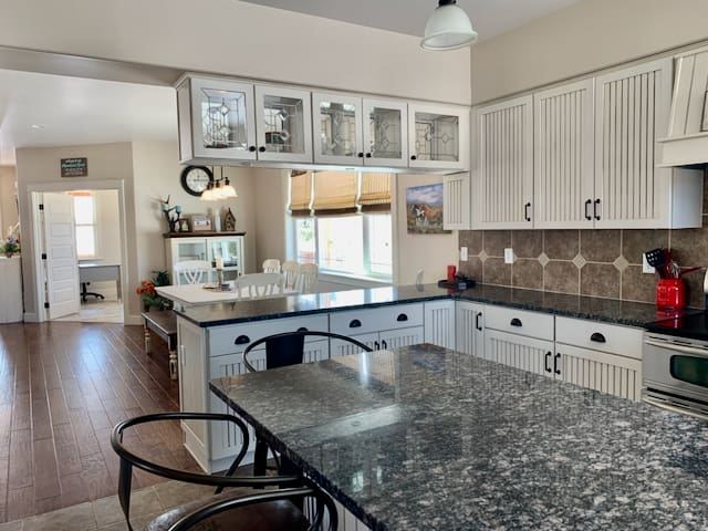 A kitchen with white cabinets and black counter tops.