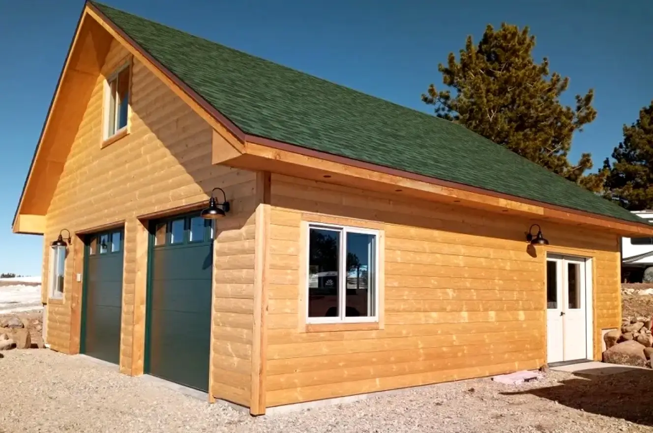 A large wooden garage with green roof and two doors.