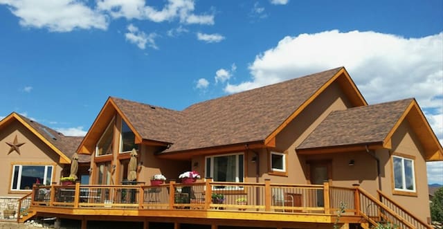 A large brown house with a deck and patio.