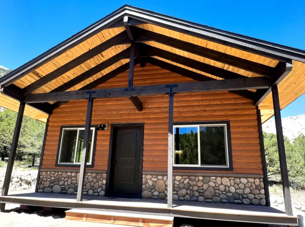 A wooden house with stone trim and wood roof.