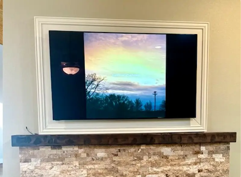 A television mounted on the wall with a picture of a sunset.