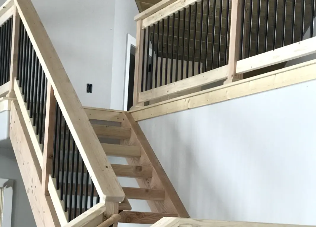 A wooden staircase with metal railing in the middle of it.