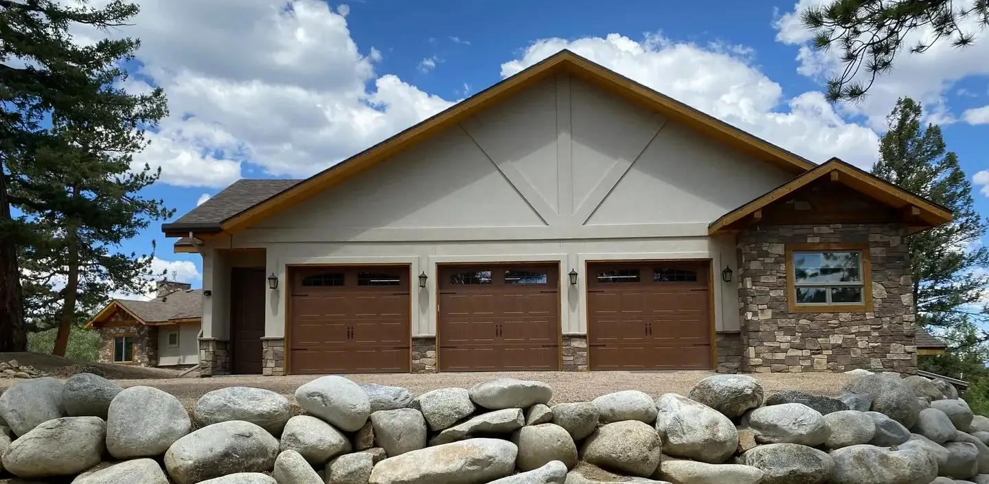 A house with three garage doors and stone wall.